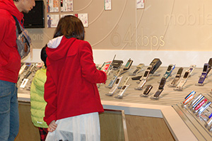 携帯電話など、移動体通信の展示を見る親子の写真